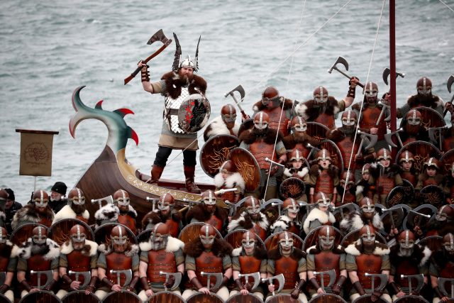 Vikings stand to attention on a galley.