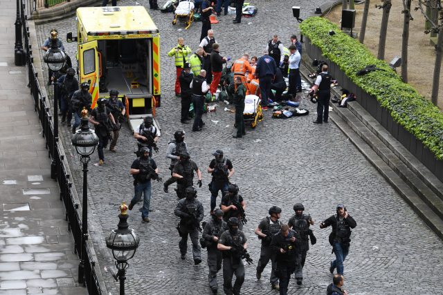 Armed police walk past emergency services