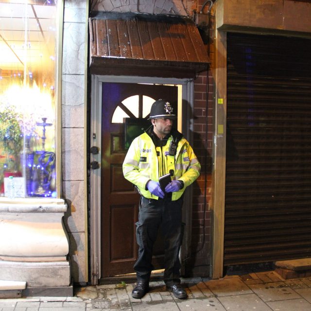 A police officer stands outside the flat which was raided overnight