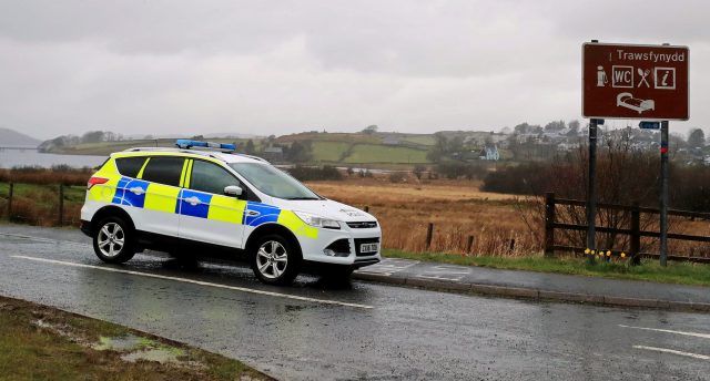 A police car passes a sign near Trawsfynydd in the Snowdonia mountain range in north Wales near where the wreckage has been discovered of a Twin Squirrel helicopter which went missing Wednesday while flying to Dublin from the south of England.