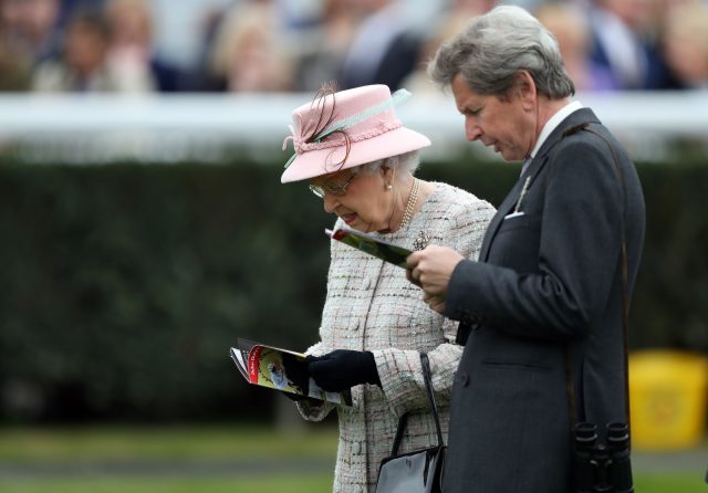 Queen Elizabeth II and her Bloodstock and Racing Advisor John Warren check the racecard as she attends the Dubai Duty Free Spring Trials and Beer Festival at Newbury Racecourse (Andrew Matthews/PA)