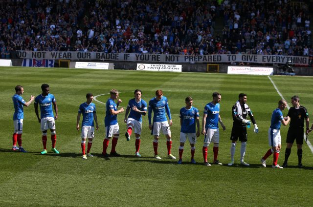 Rangers players line up at the start of the match in front of a fan banner (Andrew Milligan/PA)
