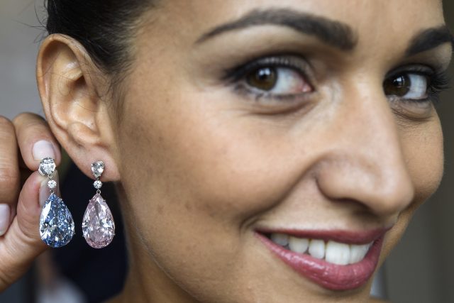 A Sotheby's employee displays the Apollo blue diamond and the Artemis pink diamond earrings  (Martial Trezzini/Keystone via AP)