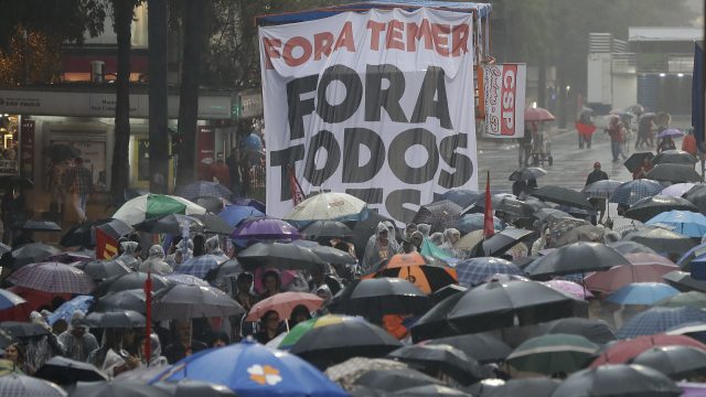 Demonstrators march against Brazil's President Michel Temer, holding a banner that reads in Portuguese 