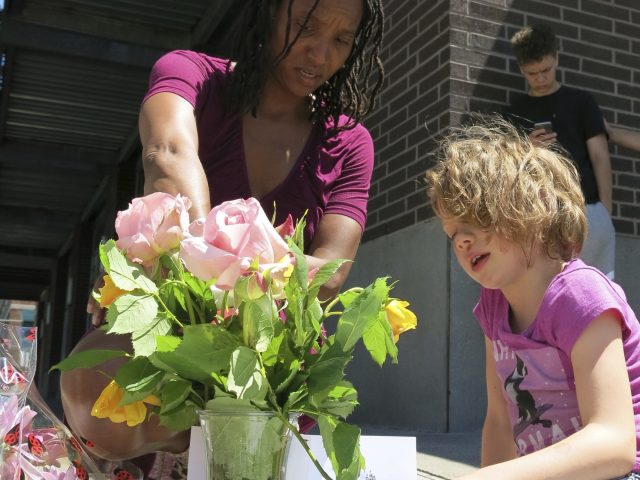 Angel Sauls and her stepdaughter Coco Douglas lay flowers at a memorial in Portland (Gillian Flaccus/AP)