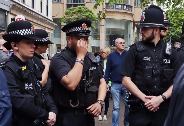 A police officer wipes away tears as he looks at flowers and tributes left in St Ann's Square in Manchester