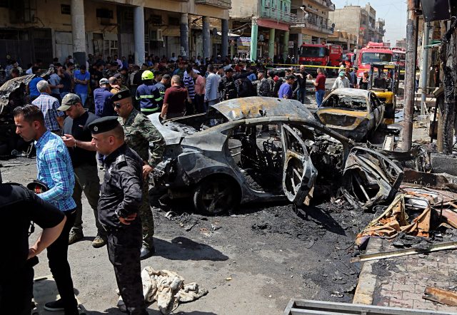 Iraqi security forces and civilians inspect the site of a deadly bomb attack, in Baghdad 