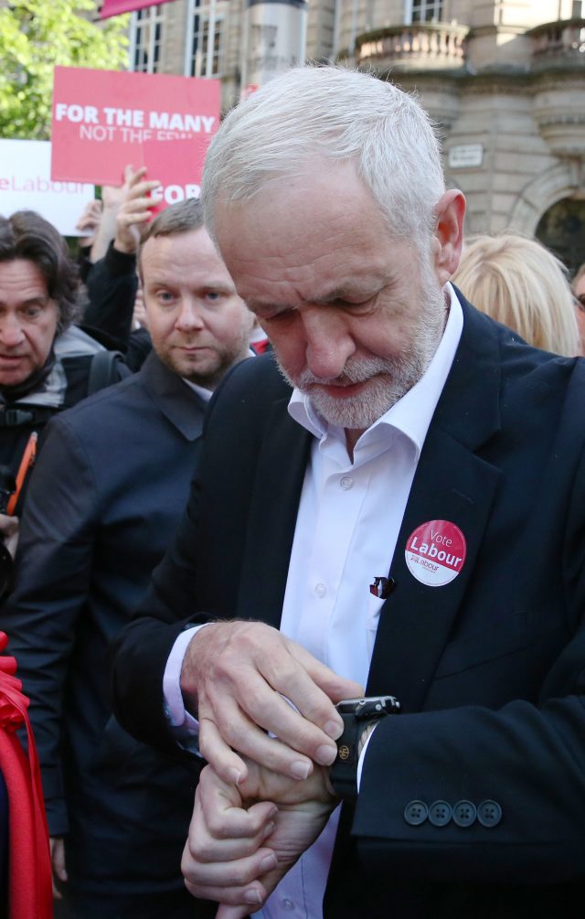 Jeremy Corbyn checks his watch during a rally in Glasgow