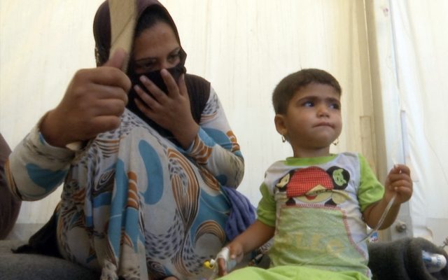 In this frame grab from video, a woman looks at her daughter who was taken ill with suspected food poisoning in the Hassan Sham U2 camp (Balint Szlanko/AP)