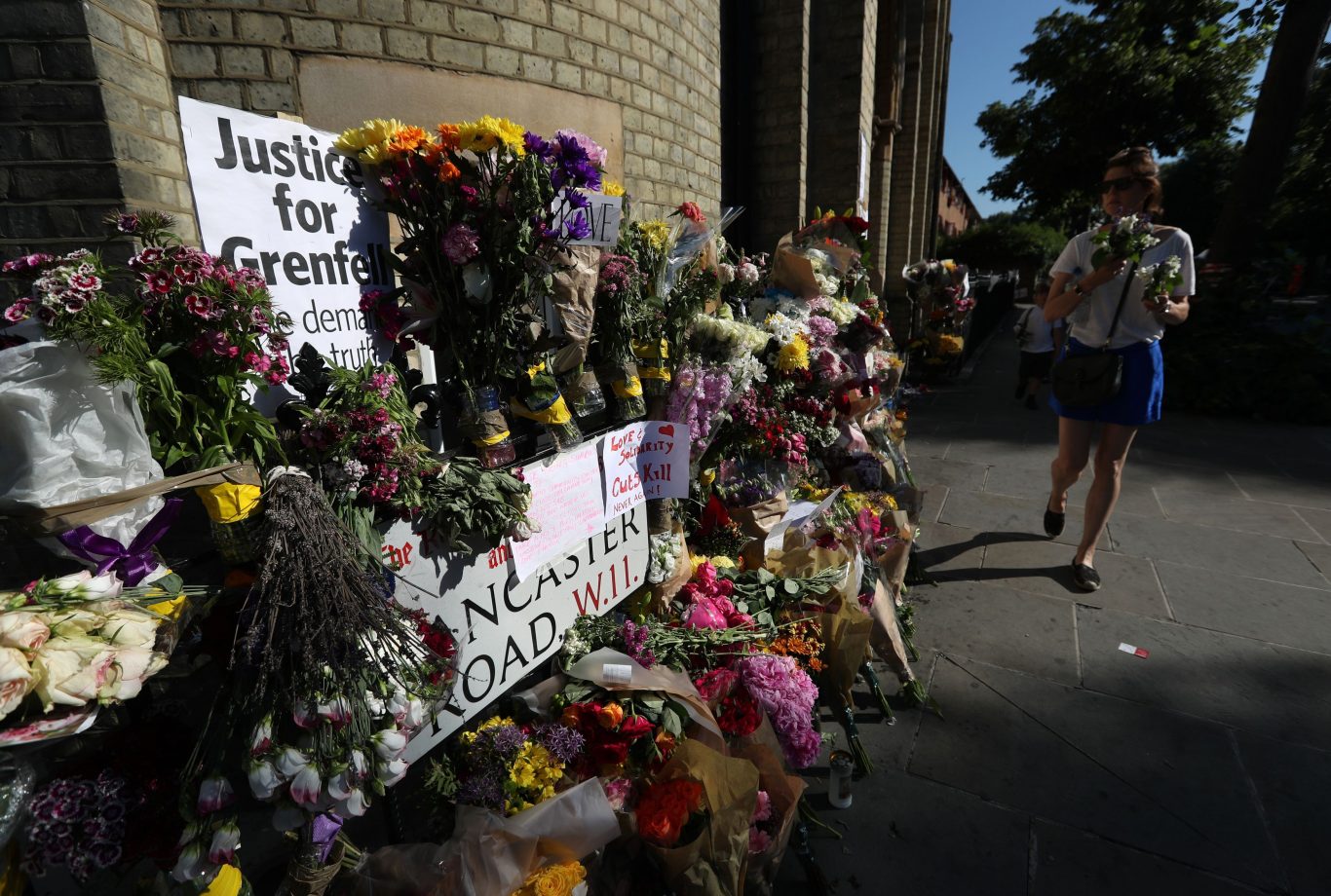 People walk past floral tributes outside Notting Hill Methodist Church (Jonathan Brady/PA)