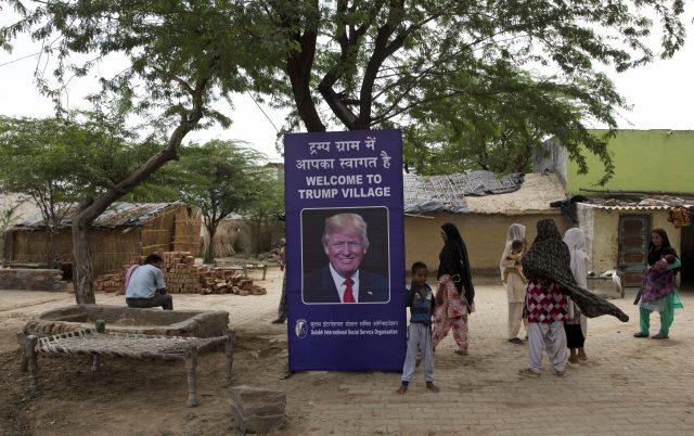 Indian village women stand next to a photograph of Donald Trump