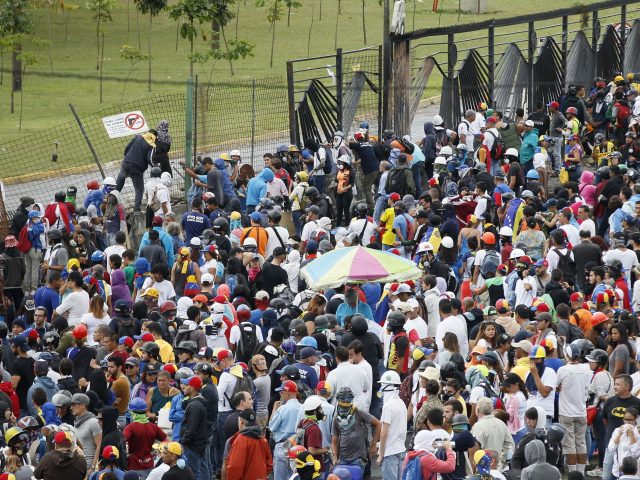 People march next to the fence of La Carlota air base during a protest on the Francisco Fajardo highway