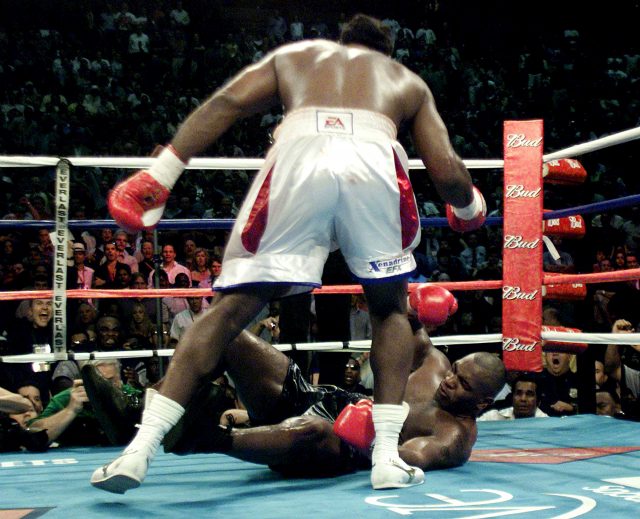 Lennox Lewis stands over Mike Tyson in their 2002 fight