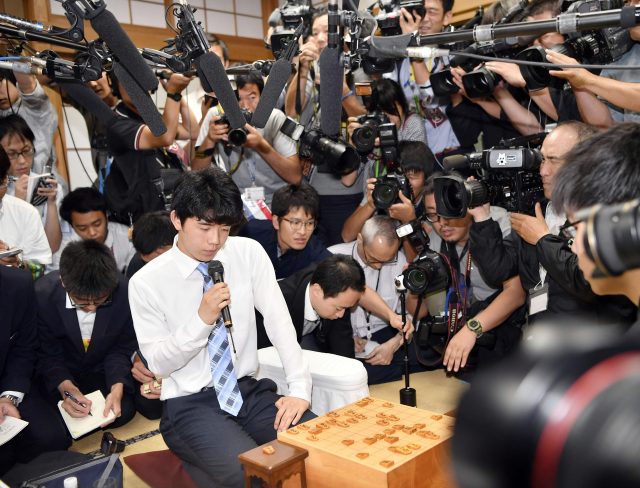 Sota Fujii, centre, is surrounded by media after Fujii defeated Yasuhiro Masuda to break a 30-year-old record with his 29th win in a row, in the qualifying round of a major tournament in Tokyo (Iori Sagisawa/Kyodo News via AP)