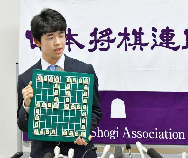 Sota Fujii holds shogi board with a number of 29 after Fujii defeated Masuda to break a 30-year-old record with his 29th win in a row (Kyodo News via AP)
