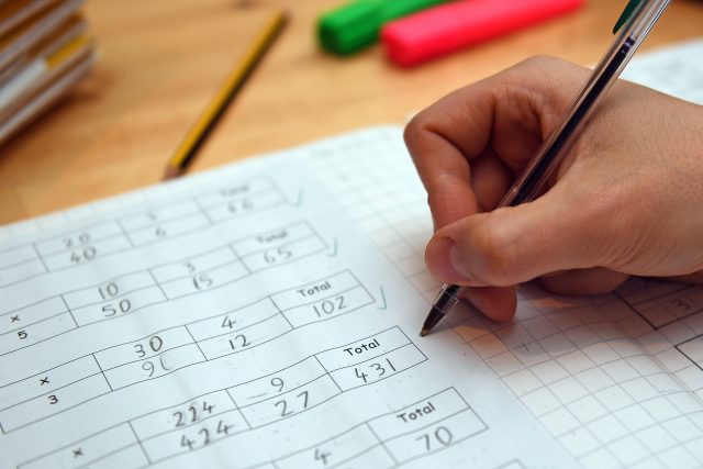 A primary school teacher marking a pupil's maths homework.