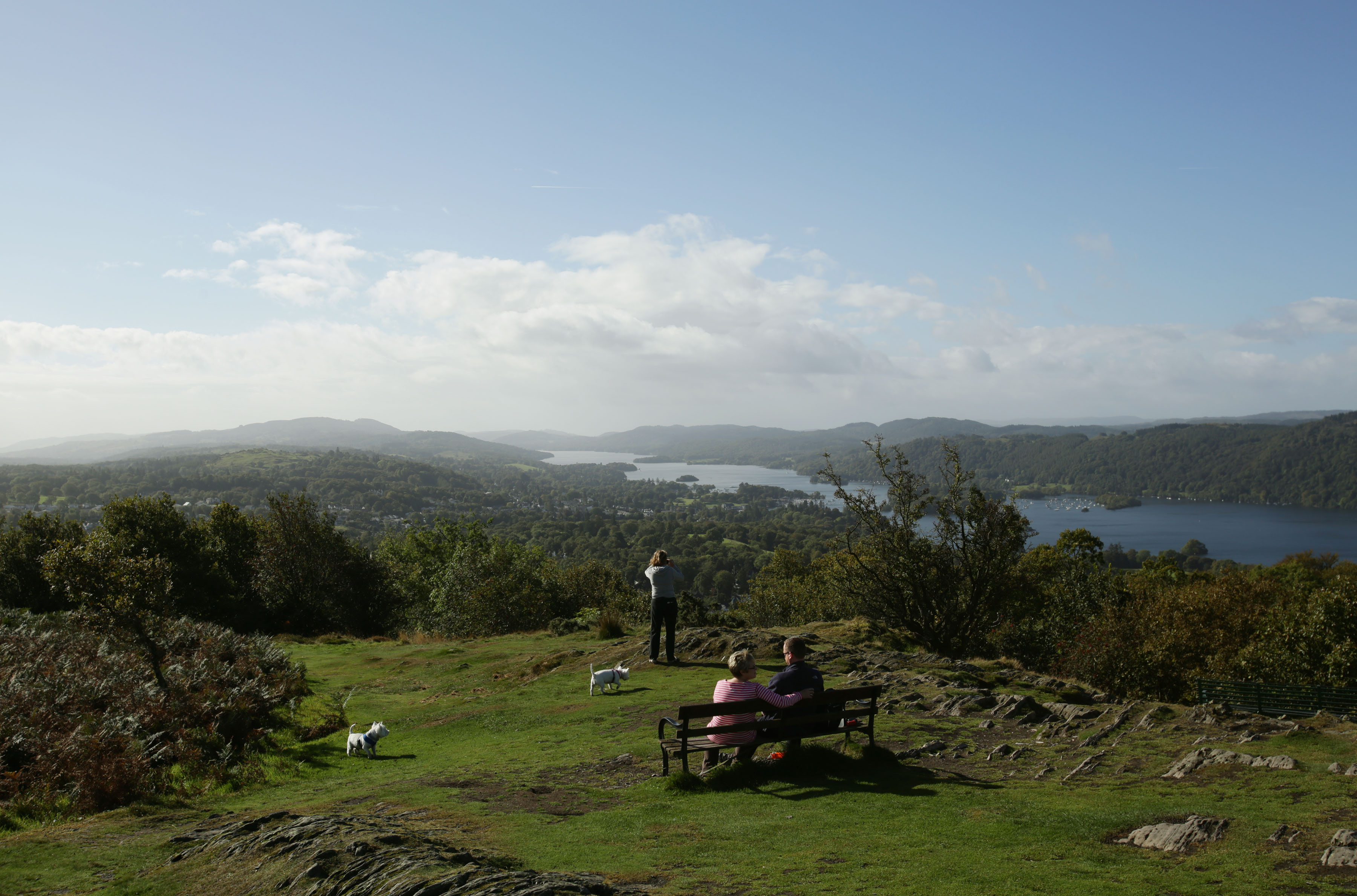 Visitors enjoying the view of Lake Windermere from the summit of Orrest Head, in the Lake District, Cumbria. 