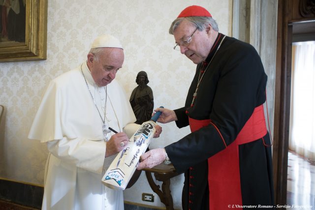 Pope Francis signs a cricket bat he received from Cardinal George Pell in 2015 (AP)