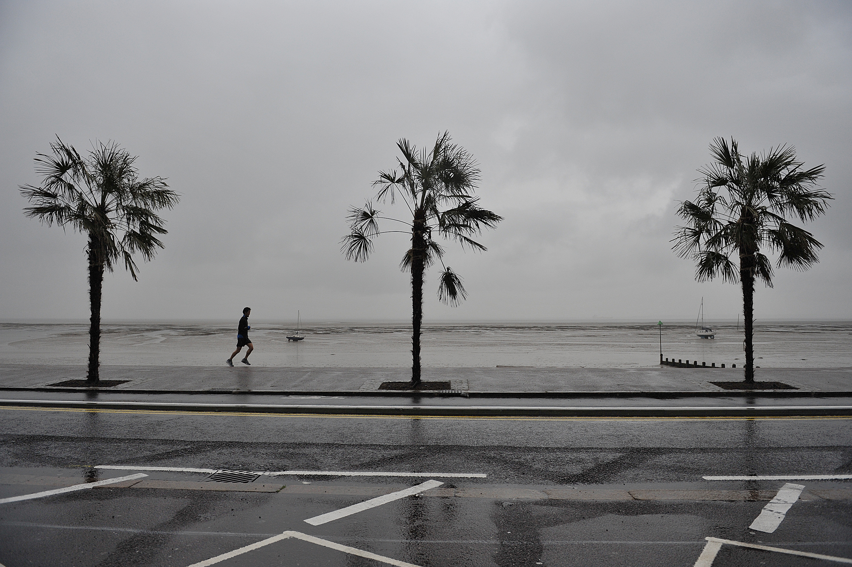 A runner passes palm trees on the promenade at Southend, Essex, as heavy rain and high winds hit much of the UK during the May Bank holiday.