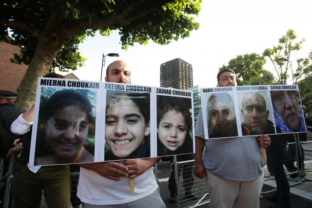 Protesters hold pictures of the victims (PA)
