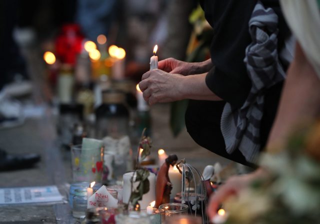 People place candles at the memorial wall near the Grenfell Tower