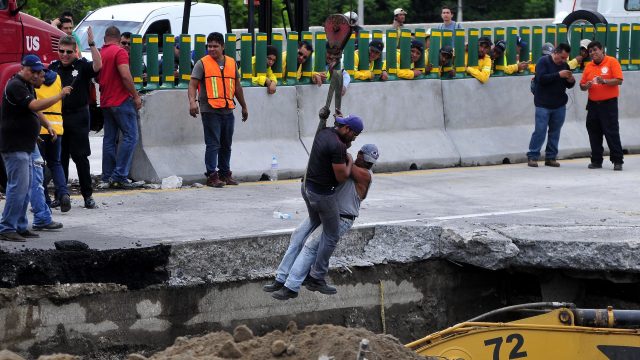 Rescue workers are lowered into the sinkhole that appeared in the Mexican road