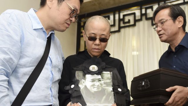 Liu Xia, wife of Nobel Peace Prize winner Liu Xiaobo, holds a portrait of him during his funeral (Shenyang Municipal Information Office/AP)