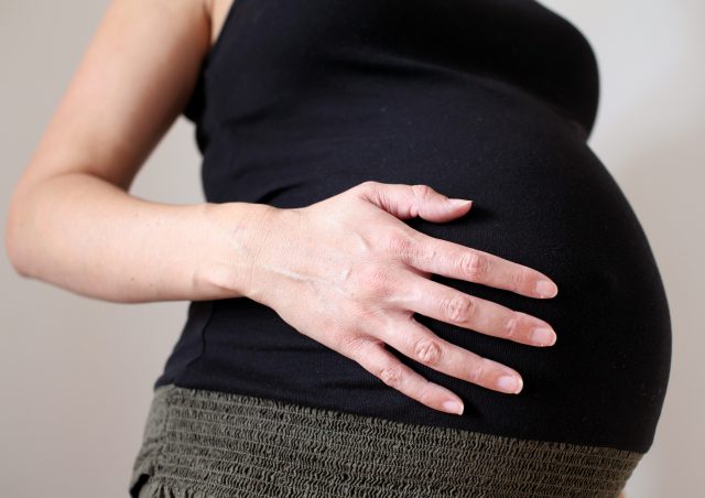 A pregnant woman holds her stomach