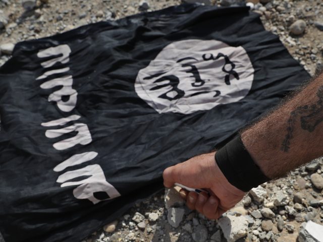 A militia member burns an Islamic State flag in Raqqa (Hussein Malla/AP)