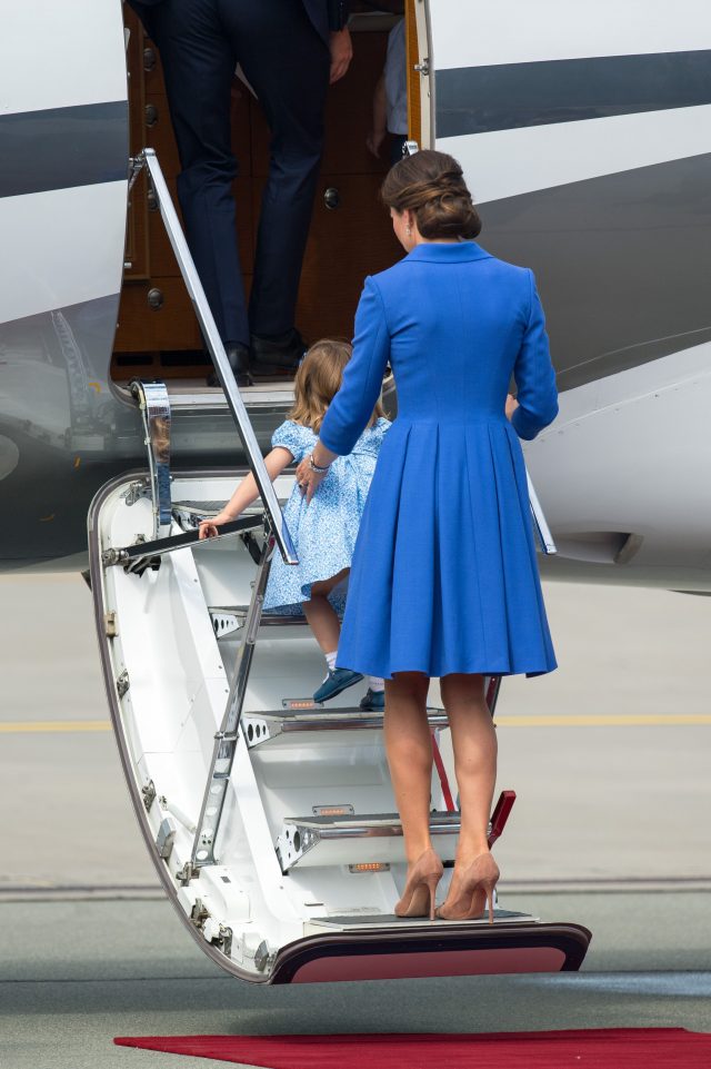 Princess Charlotte crawls up the plane steps, watched by the Duchess of Cambridge