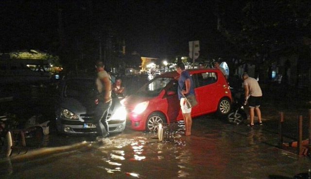 People try to move the cars from a flooded coastal road in Kos