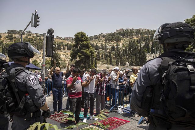 Israeli police officers stand guard as Palestinians pray outside the Lion's Gate in Jerusalem's Old City. (Tsafrir Abayov/AP)