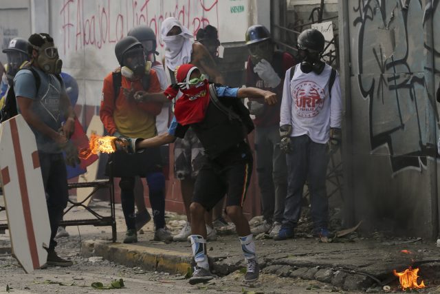 An anti-government protester prepares to throw a homemade petrol bomb 
