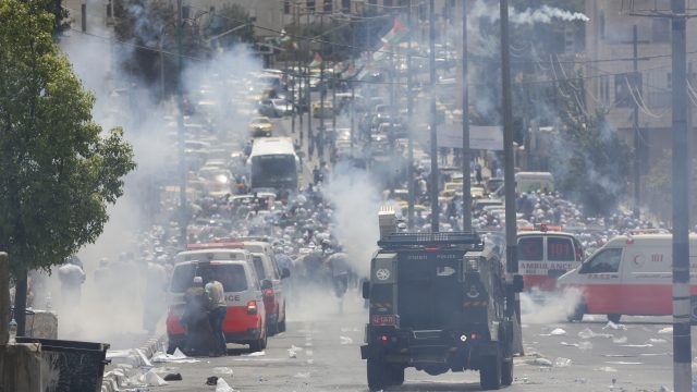 Palestinians run away from tear gas shot by Israeli army during clashes in the West Bank on Friday night