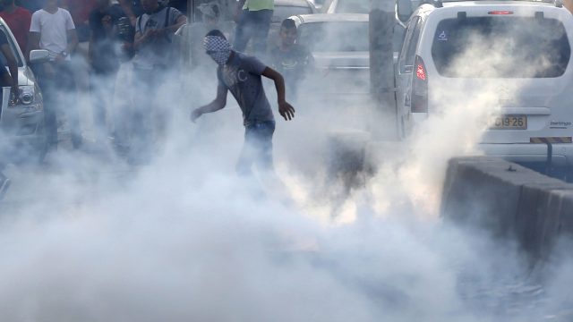 A Palestinian protester stands in tear gas during clashes near the Qalandia checkpoint