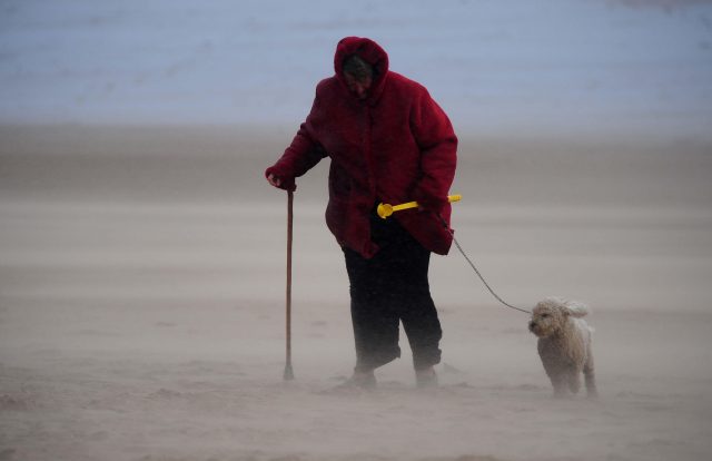 A woman battles her way through a sand storm on Tynemouth beach