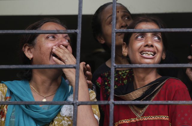 Relatives of people trapped under the rubble of the collapsed building watch the rescue operation in Mumbai (Rafiq Maqbool/AP/PA)