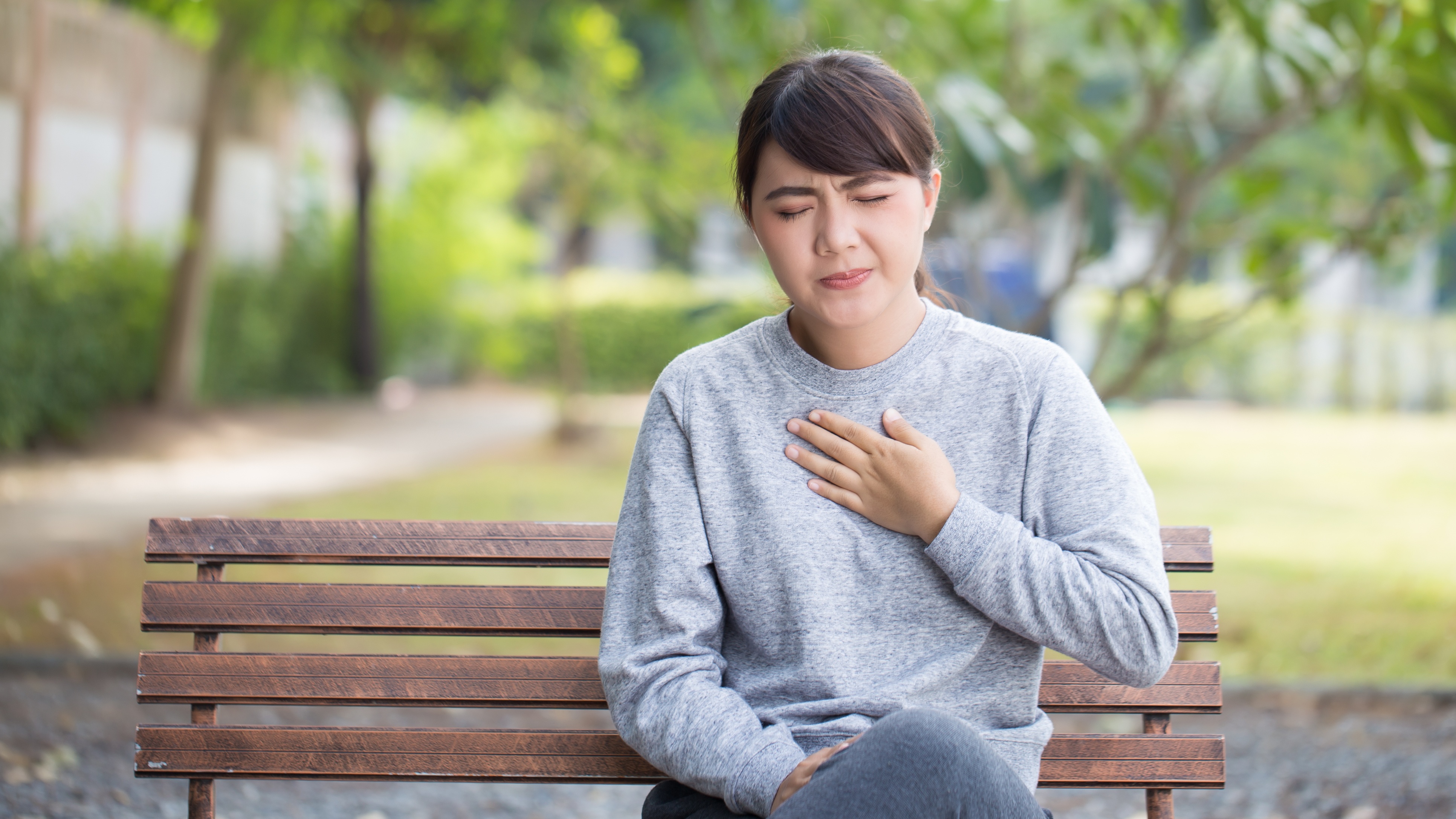 Generic photo of young woman on a park bench experiencing pain in her chest (ThinkStock/PA)