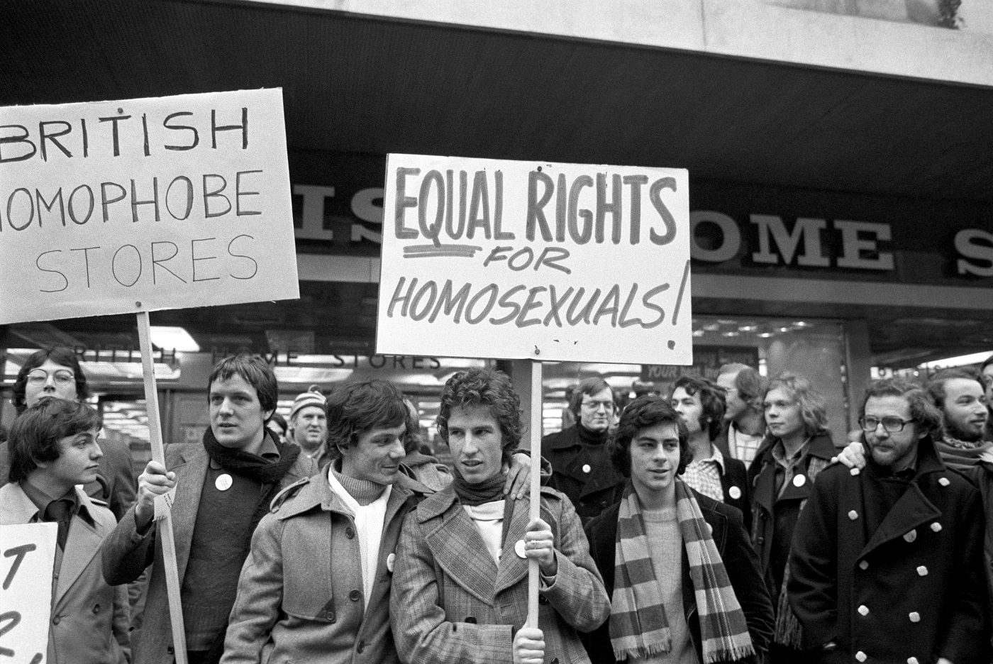 A banner carrying homosexual Tony Whitehead (centre) and his friend John Roman Baker (white scarf) during a protest by supporters of the Campaign for Homosexual Equality at a British Home Stores in London's Oxford Street, over the forced resignation of Mr Whitehead after being shown on TV kissing and cuddling Mr Baker.