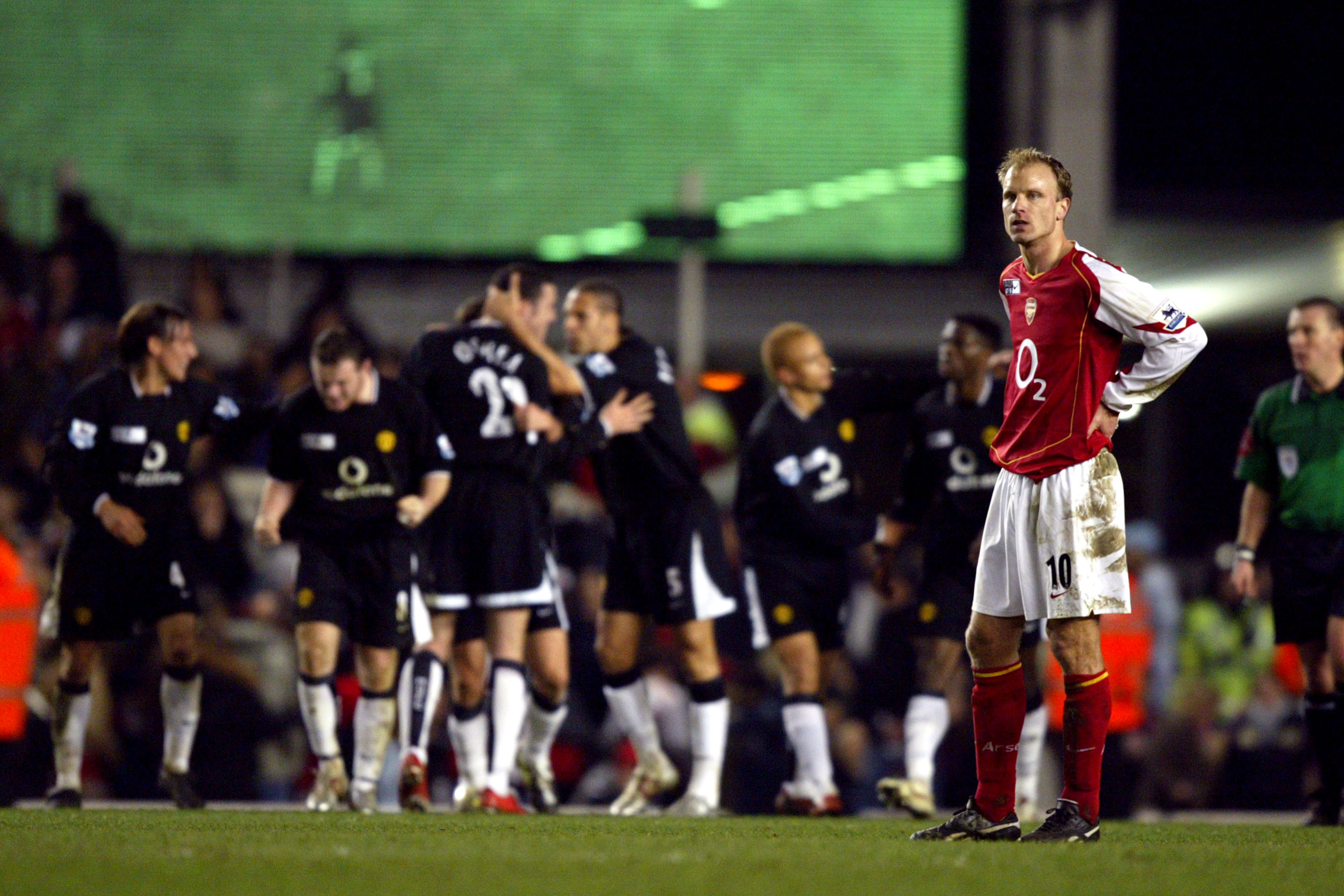 Manchester United players celebrate while Dennis Bergkamp looks on