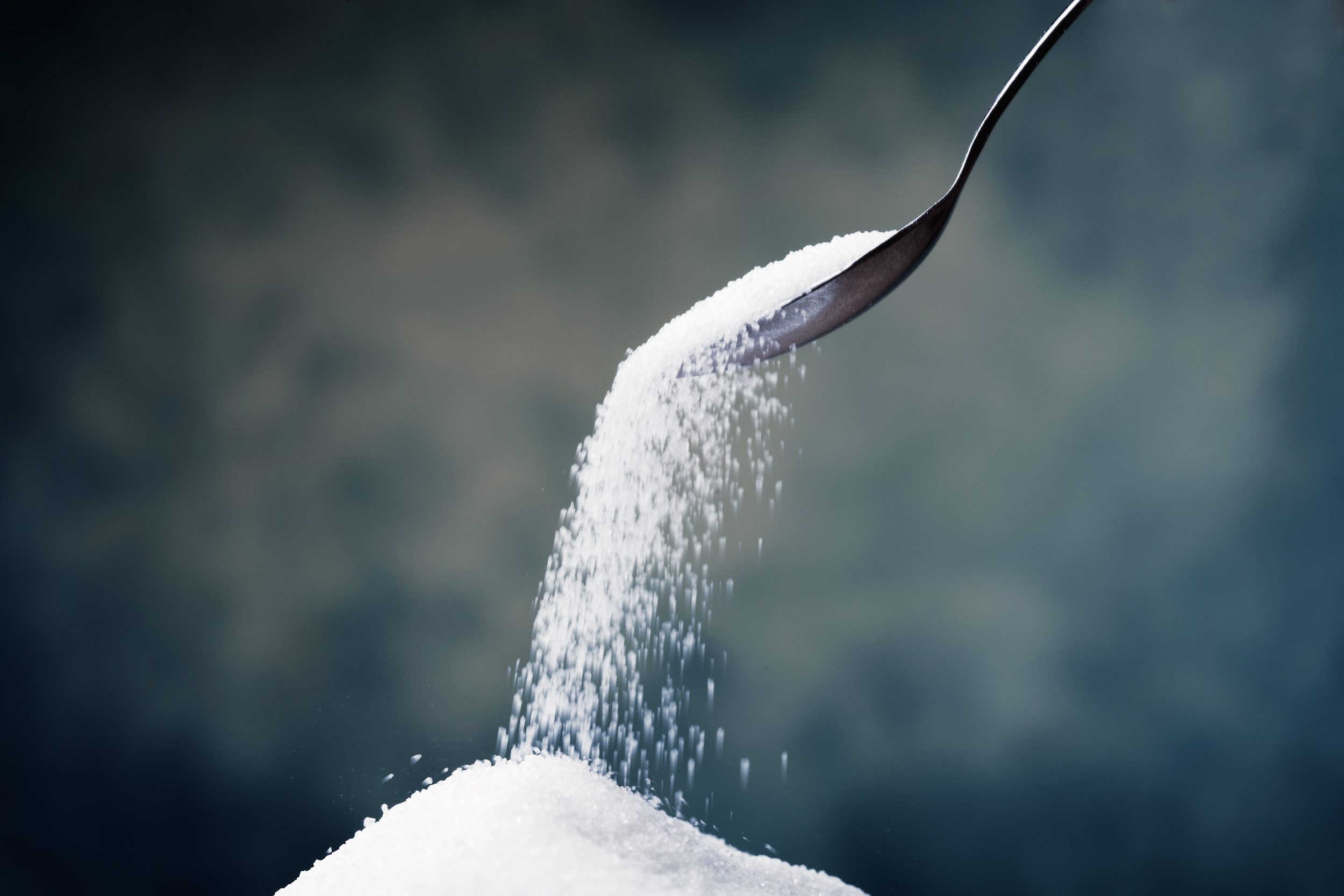 A spoon pours sugar