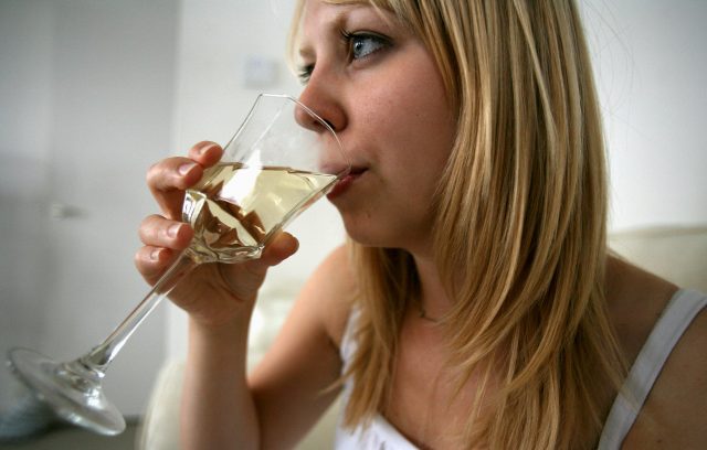 A woman drinking a glass of white wine