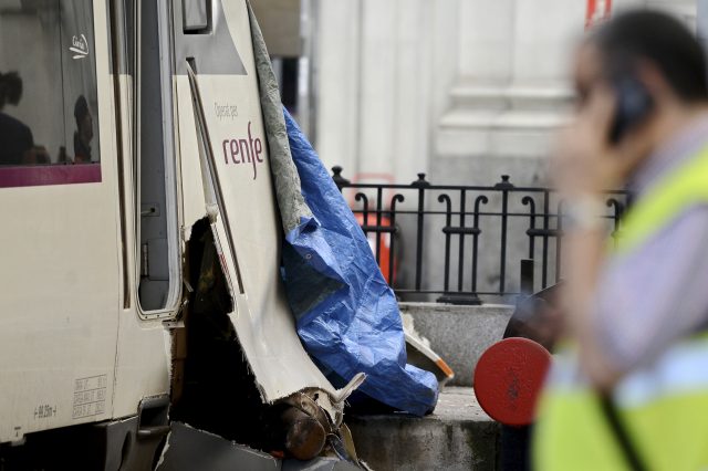 A worker speaks on his phone next to the damaged train