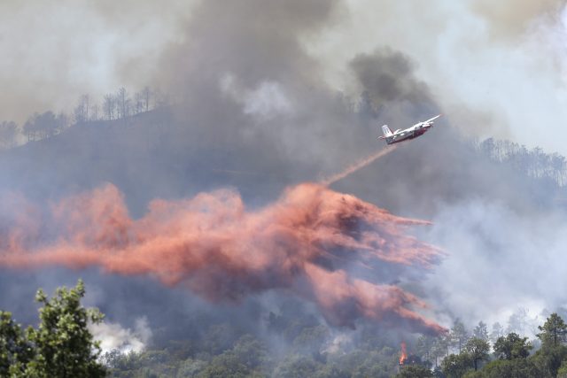 A firefighting plane drops fire retardant over a forest in the outskirts of La Londe-les-Maures on the French Riviera (Claude Paris/AP)
