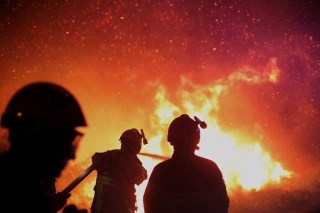 Firefighters spray water as they try to douse a fire near the village of Biguglia, Corsica (Raphael Poletti/AP)