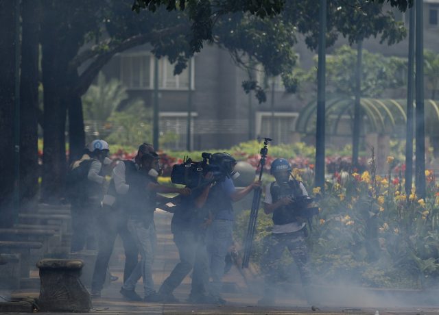 Journalists take cover from tear gas in Caracas. (Ariana Cubillos/AP)