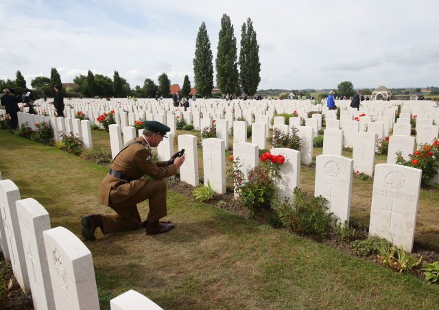 A man in uniform photographs gravestones at the Tyne Cot Commonwealth War Graves Cemetery (Yui Mok/PA)