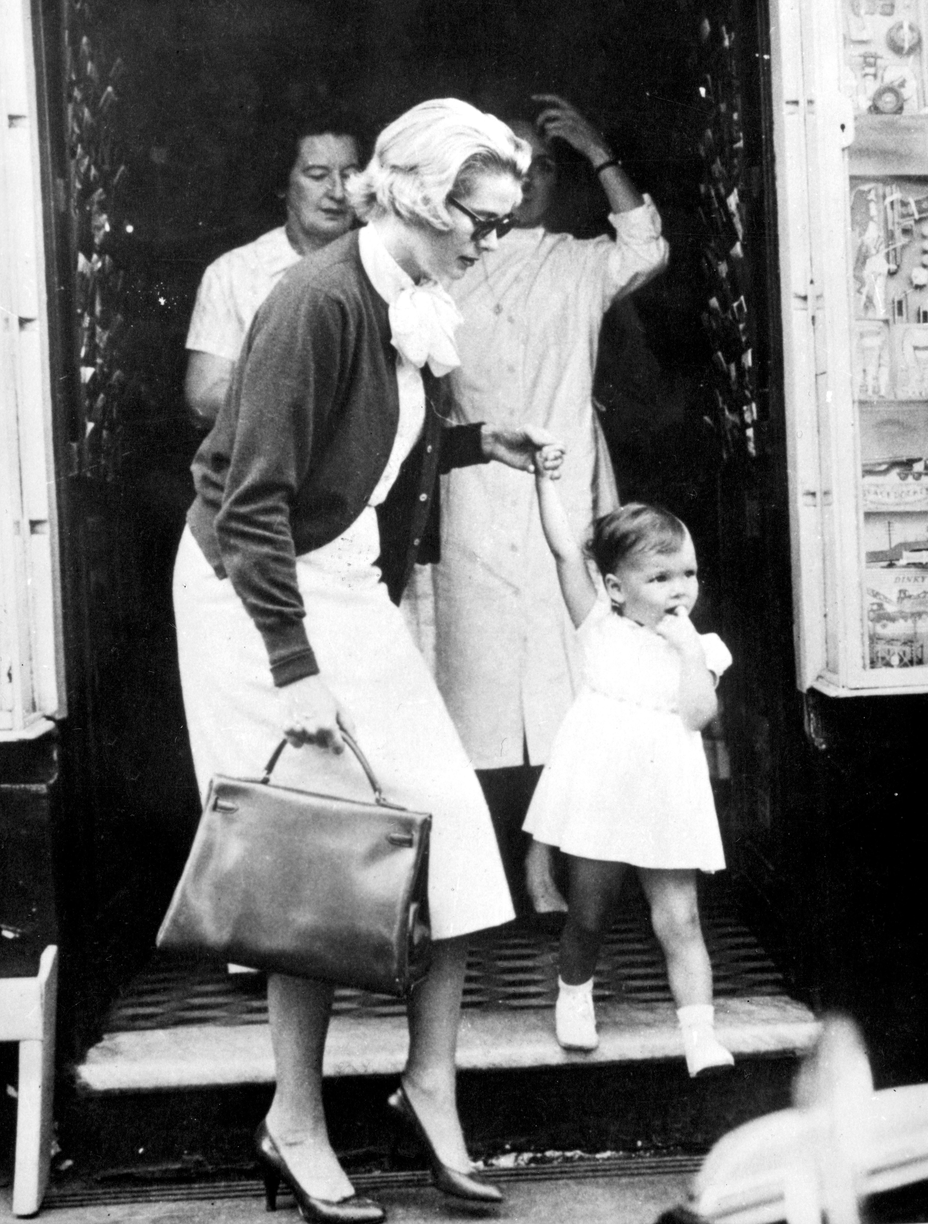 Princess Grace holds the hand of her daughter, Princess Caroline, during a shopping trip