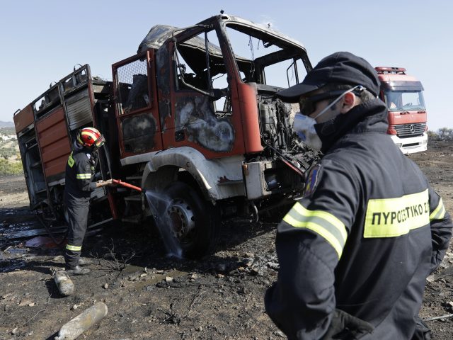 Firefighters douse a vehicle near Kalyvia in Greece (Thanassis Stavrakis/AP)