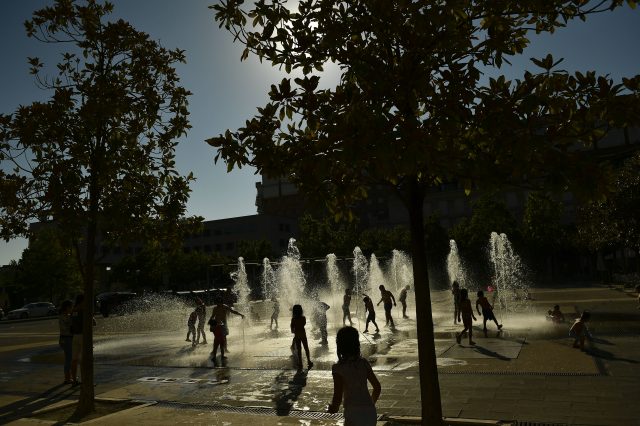 People cool off in a fountain in Pamplona